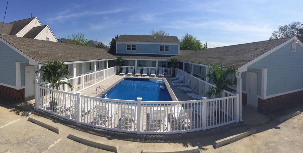 a house with a swimming pool and a white fence at Boardwalk Beach Inn in Point Pleasant Beach