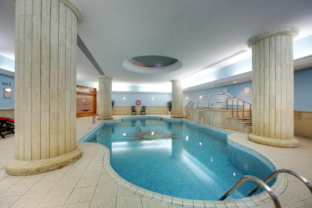 a large swimming pool in a hotel with columns at Vivaldi Hotel in St. Julianʼs