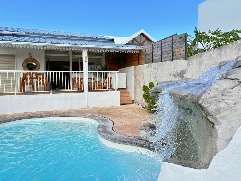una piscina con cascada frente a una casa en Villa OCEANE, en Sainte-Marie