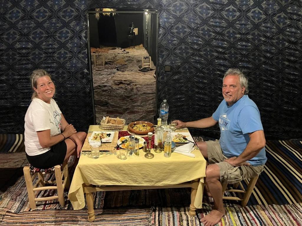 um homem e uma mulher sentados à mesa em Merzouga Deeper Camp em Merzouga