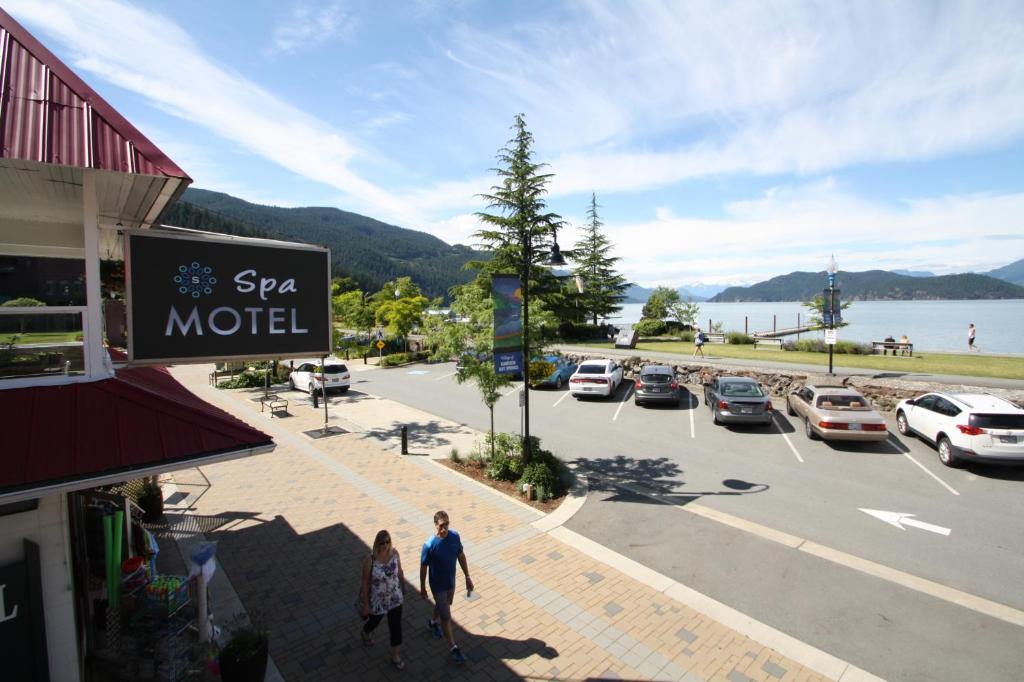 a man and woman walking down a street next to a parking lot at Harrison Spa Motel in Harrison Hot Springs