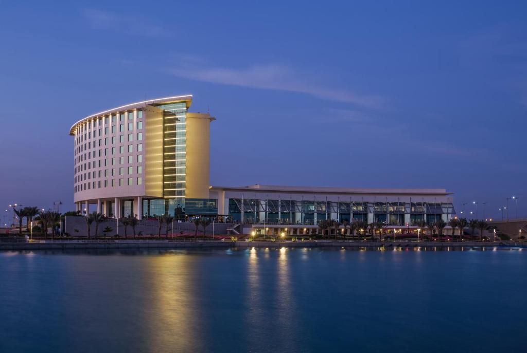 a large building next to a large body of water at Bay La Sun Hotel and Marina - KAEC in King Abdullah Economic City