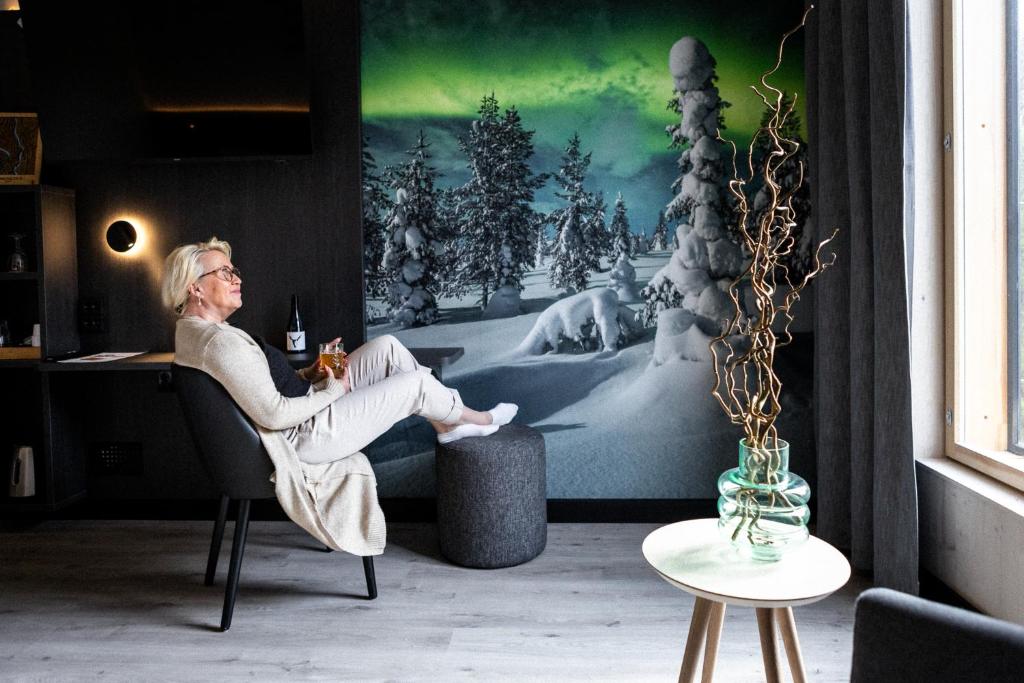 a woman sitting in a chair in a room at Hotelli Sodankylä in Sodankylä