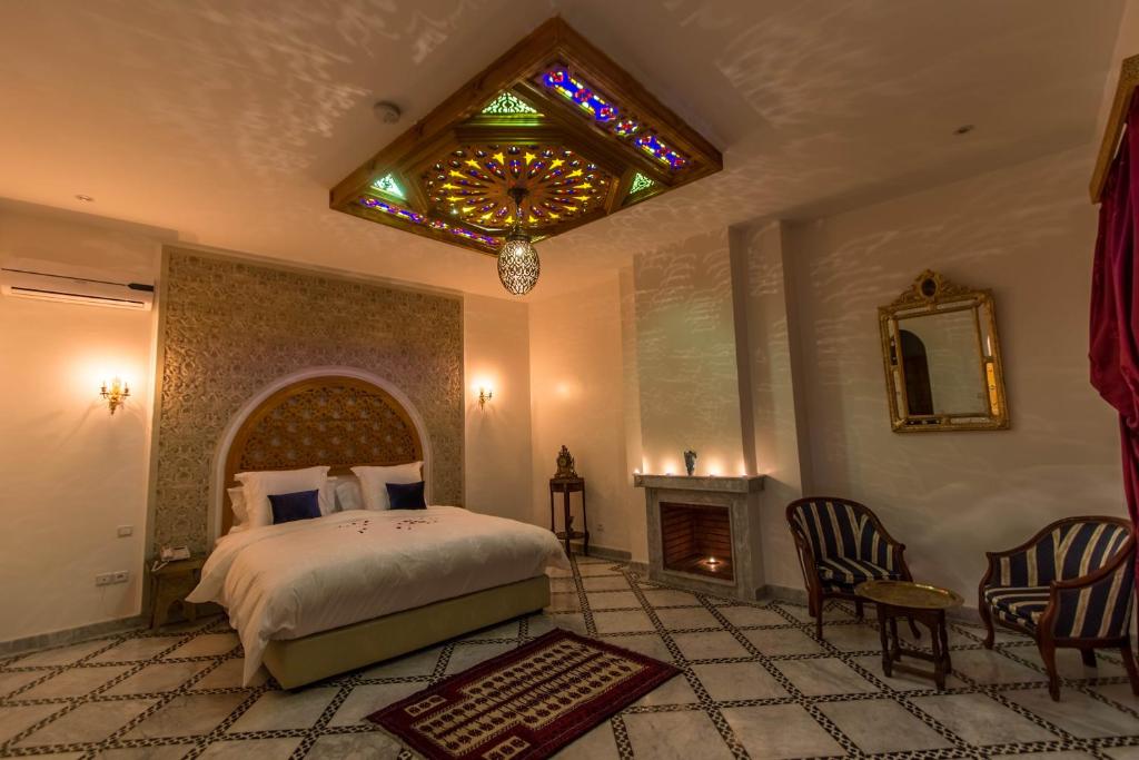 a bedroom with a bed and a chandelier and a fireplace at Riad Amor - Suite & Spa in Fès