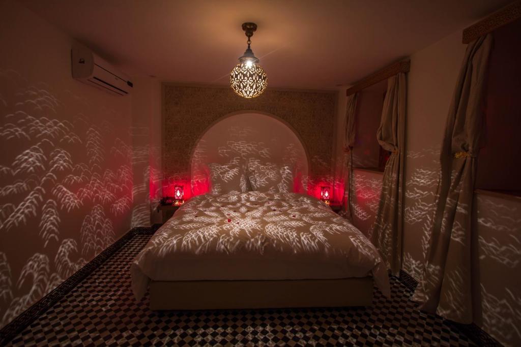 a bedroom with a bed with red lights and a chandelier at Riad Amor - Suite & Spa in Fès