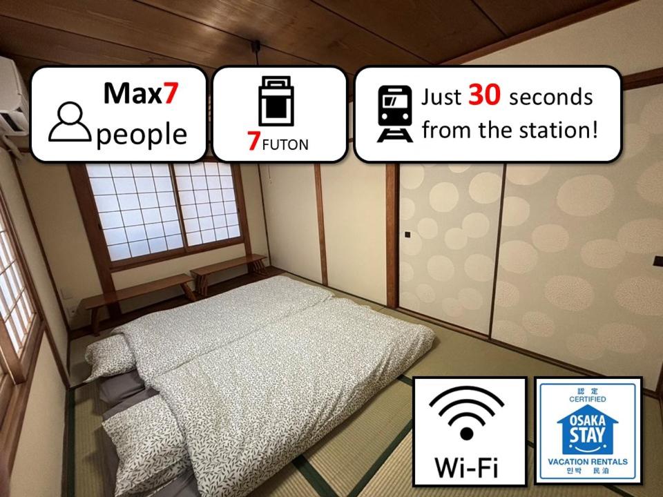 Una habitación con una cama y algunas imágenes y palabras. en DAIKOKU INN Yudo, en Osaka