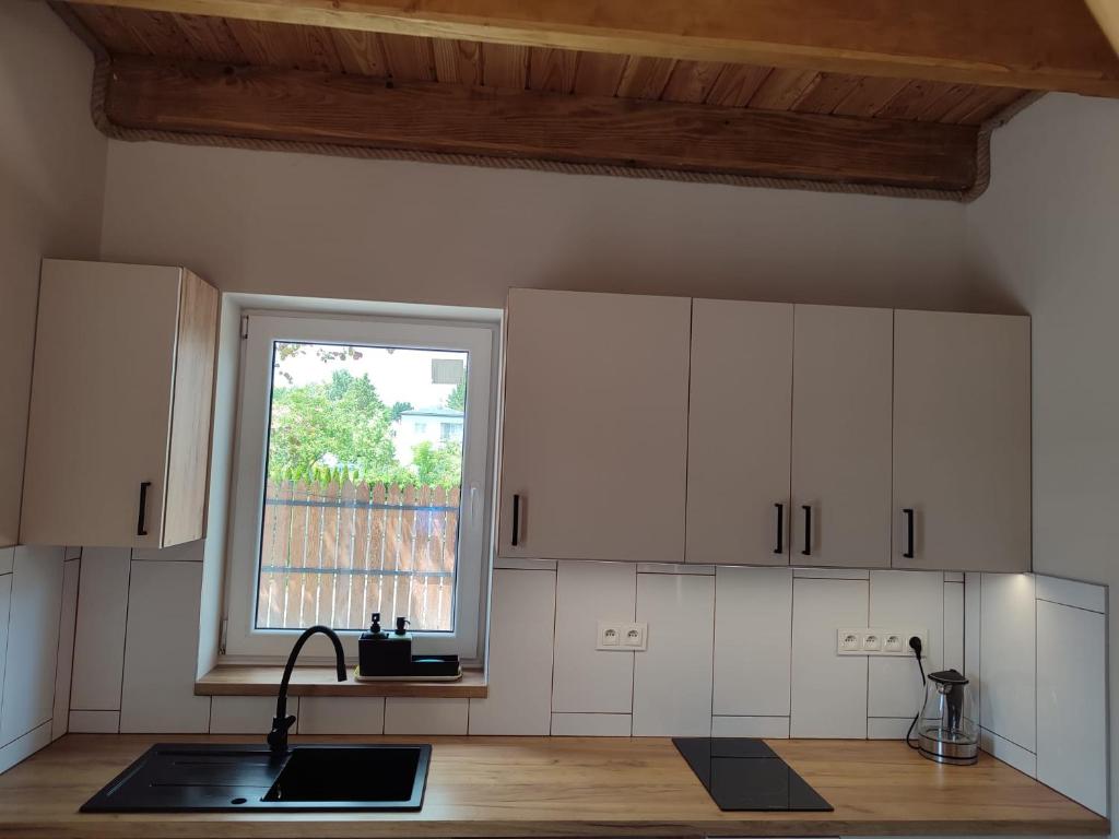 a kitchen with white cabinets and a window at Świerkowy Las in Sanok