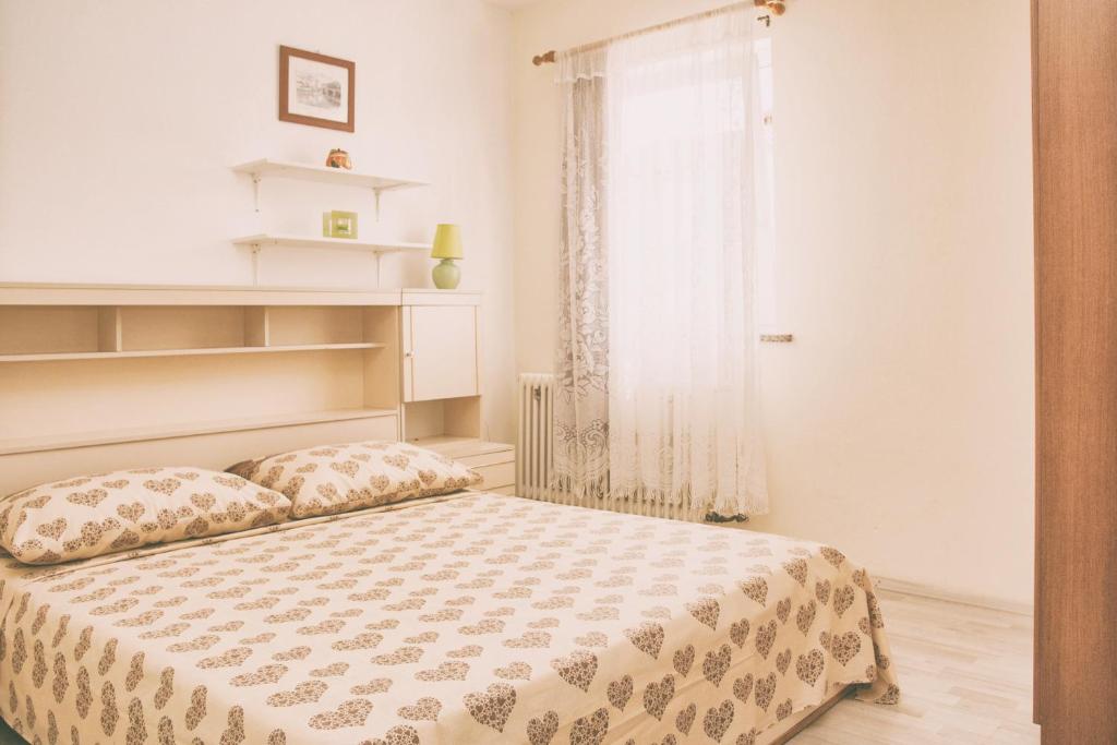 a white bedroom with a bed and a window at Apartment Kisic in Fažana