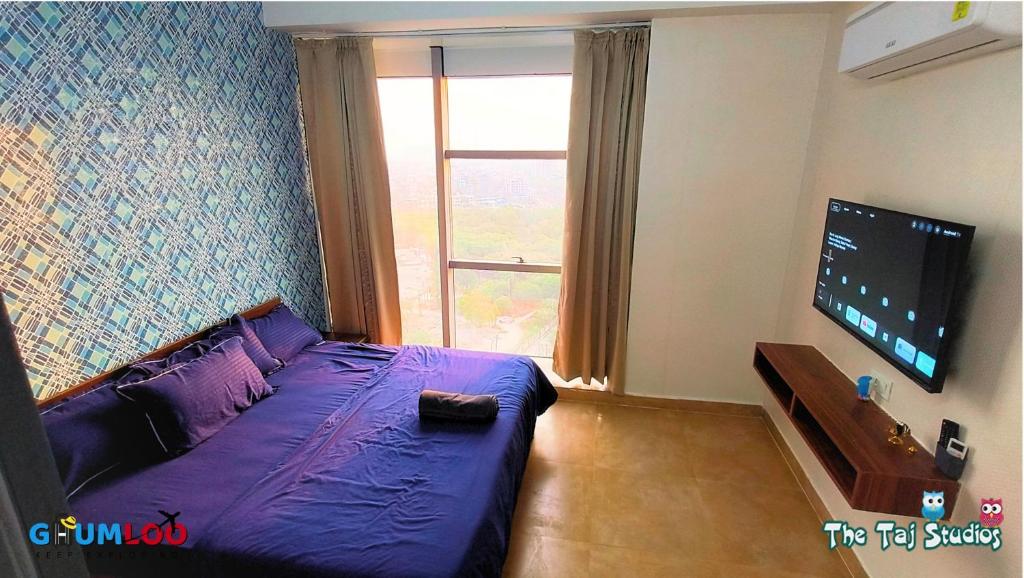 a bedroom with a purple bed and a large window at Swimming Pool with Full Equipped Studio Apartment in Noida