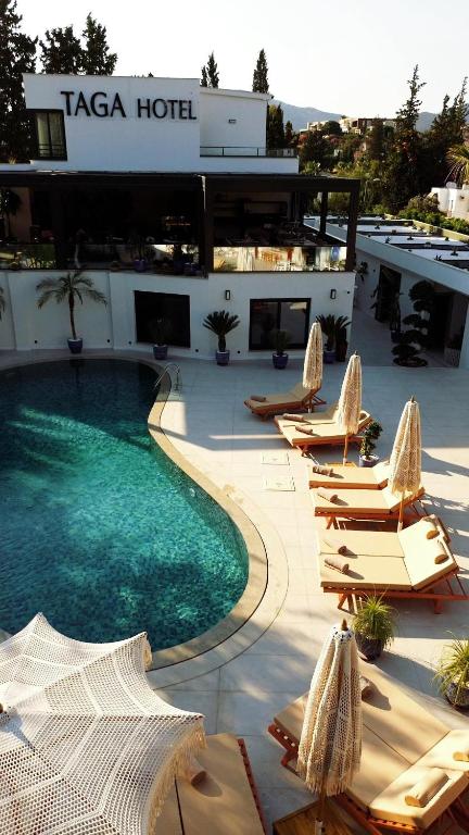 a hotel with a swimming pool and lounge chairs at Taga Hotel in Bitez