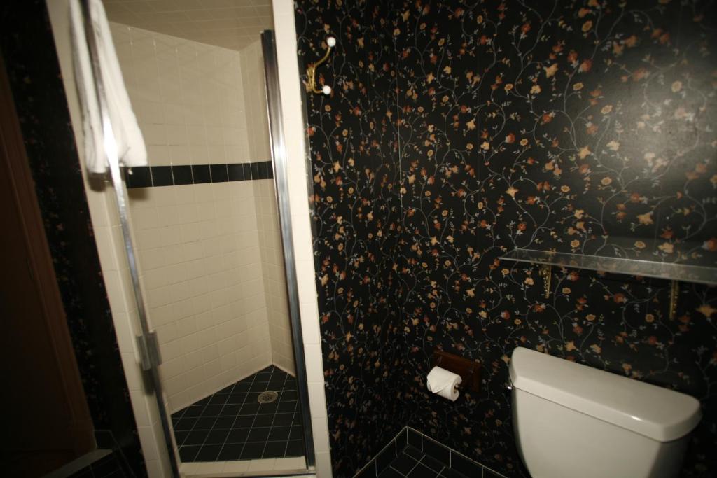 a bathroom with a shower with a toilet and a black wall at Parsonage Inn Bed and Breakfast in Saint Michaels