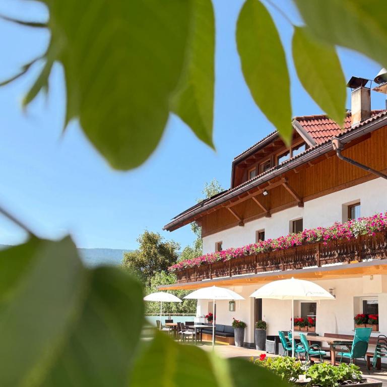 a building with tables and chairs and umbrellas at Pension Wirt am Bach in Terento