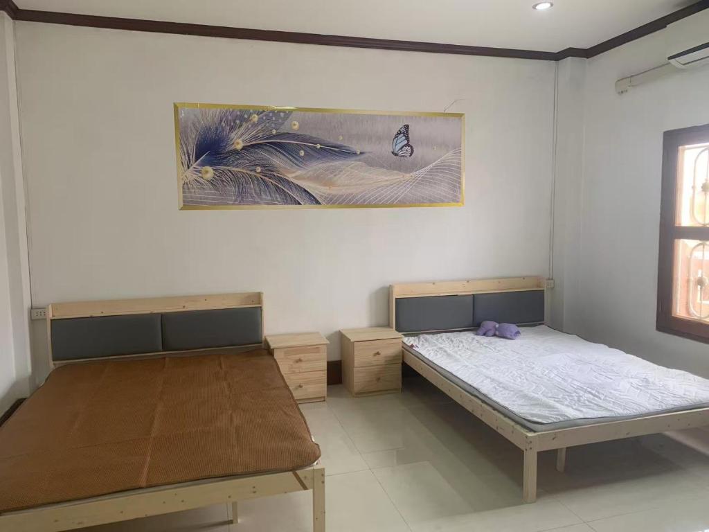 Un dormitorio con dos camas y un cuadro en la pared. en FUBON World, en Vientiane