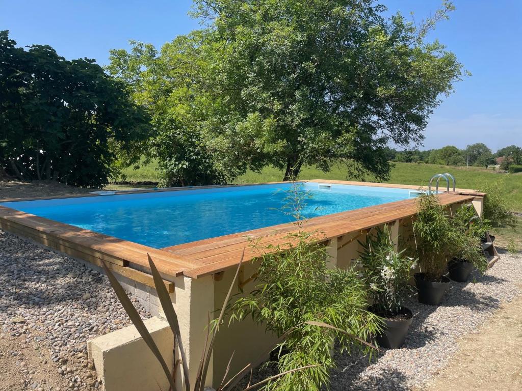 a swimming pool with a wooden deck next to a field at Maison de campagne / piscine privée in Villeréal