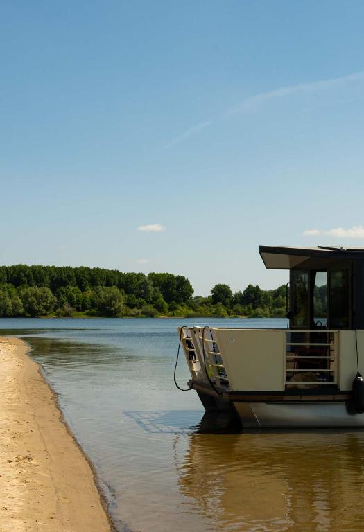 a boat sitting on the water next to a beach at Holiday Houseboats in Lith