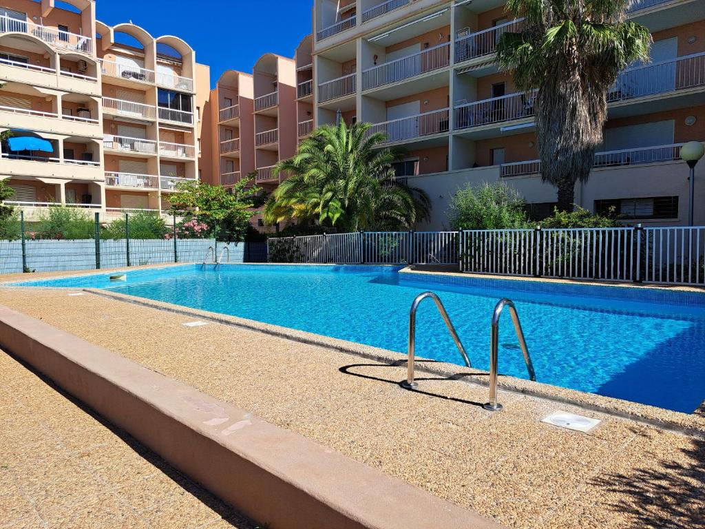 - une piscine en face d'un immeuble dans l'établissement Plage du grazel le thalassa, à Gruissan