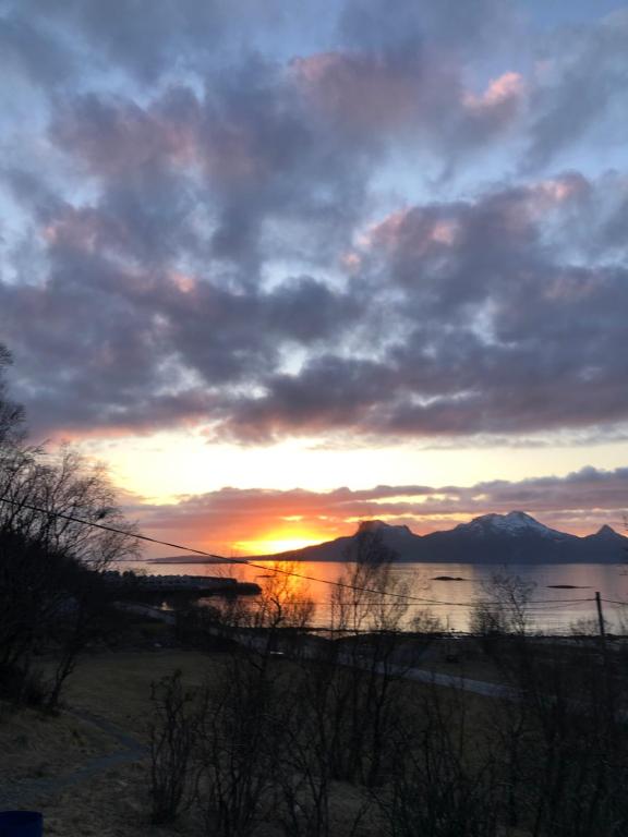 una puesta de sol sobre un cuerpo de agua con montañas en Midnight Sun Road, en Bodø