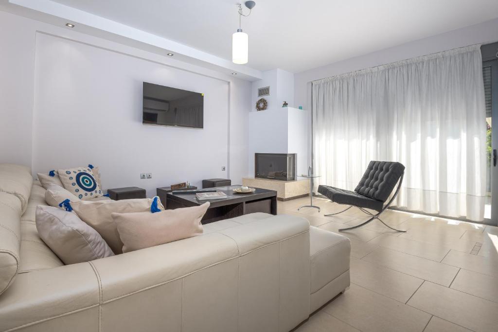 a white living room with a couch and a chair at Villa Anavil - Boutique Coastal Retreat in Varkiza in Vari