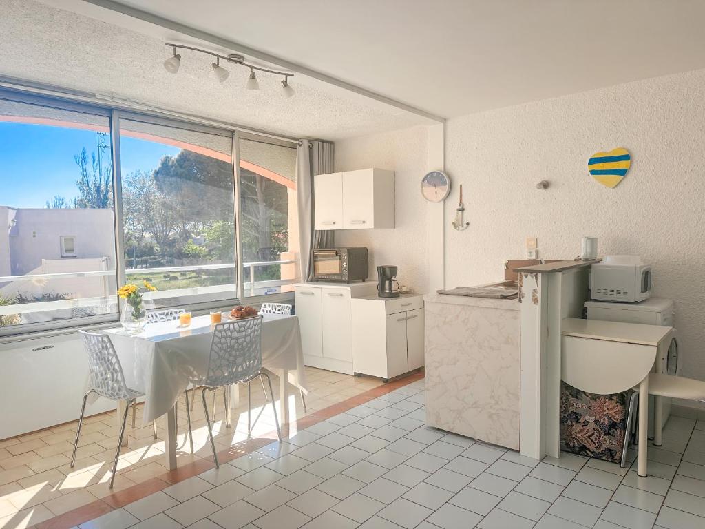 - une cuisine avec une table, une table et des chaises dans l'établissement Rosae by POM, piscine, pkg, au Cap d'Agde