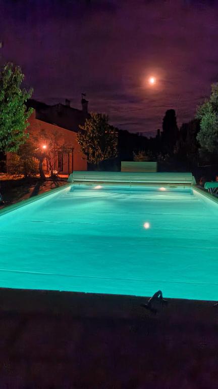 une grande piscine éclairée la nuit dans l'établissement Appartement éco-responsable avec piscine, à Châteaudouble