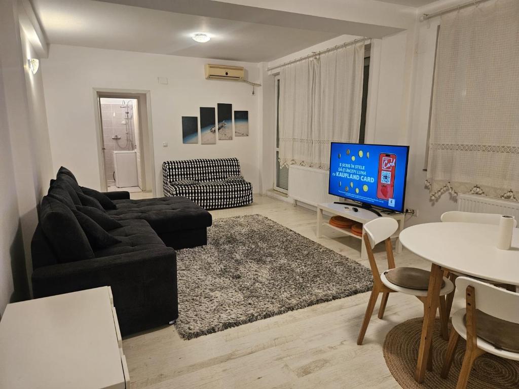a living room with a black couch and a tv at D&D Apartment in Mamaia Nord