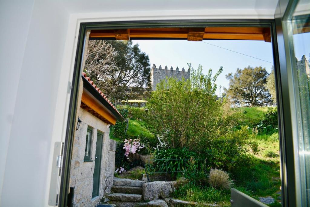 ein Fenster mit Blick auf einen Garten mit einem Schloss im Hintergrund in der Unterkunft Caminho Gerês - Heritage Eco-Cottage - jacuzzi in Lindoso