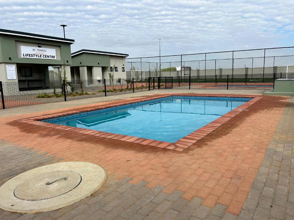 a large swimming pool in the middle of a brick courtyard at Anostars Apartments J6 in Gaborone