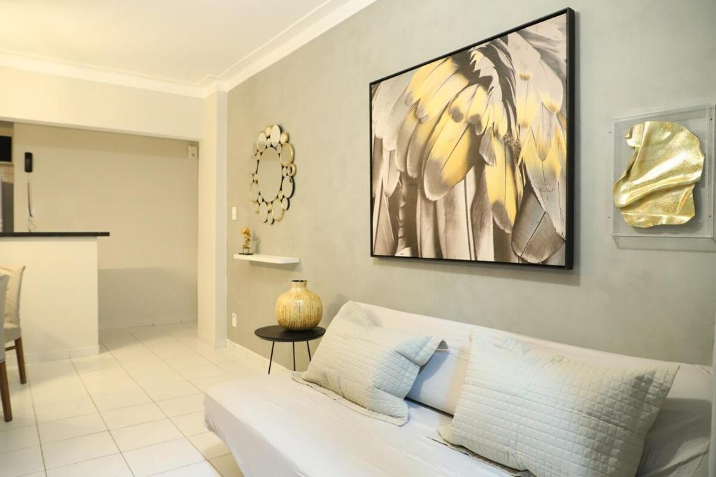 a living room with a white couch and a painting on the wall at Apartamento Atalaia Aracaju 3 quartos in Aracaju