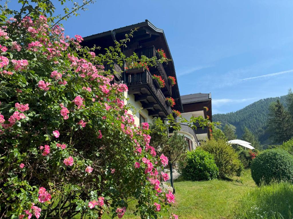 a building with pink flowers in front of it at Pension & Appartements Ronacherhof -Mountain Hideaway Slopeside in Bad Kleinkirchheim
