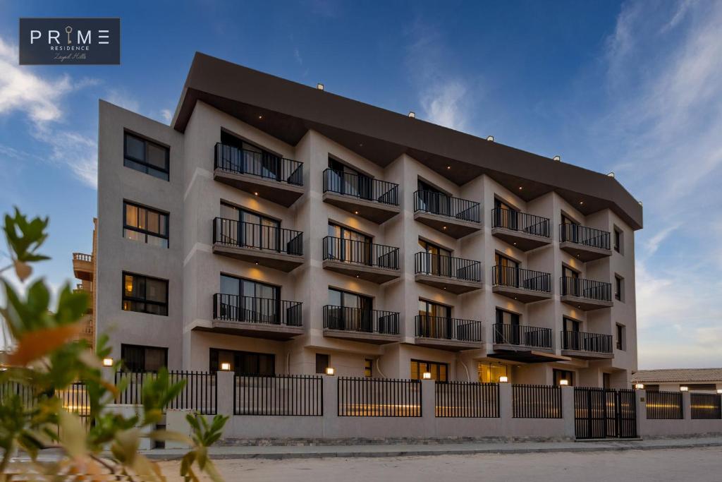 a white apartment building with a black roof at Prime Residence Zayed Hills in Sheikh Zayed