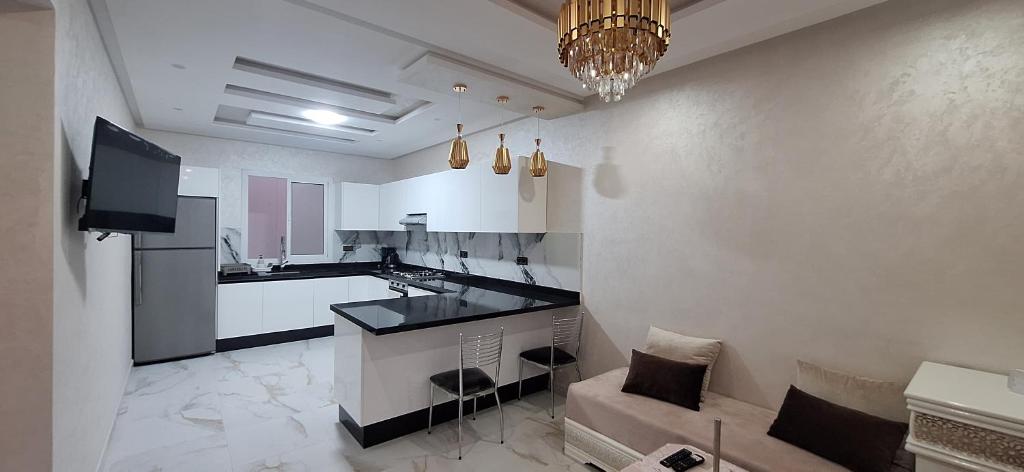 a large white kitchen with a couch and a television at Appartement à louer Al Hoceima vue mer in Al Hoceïma