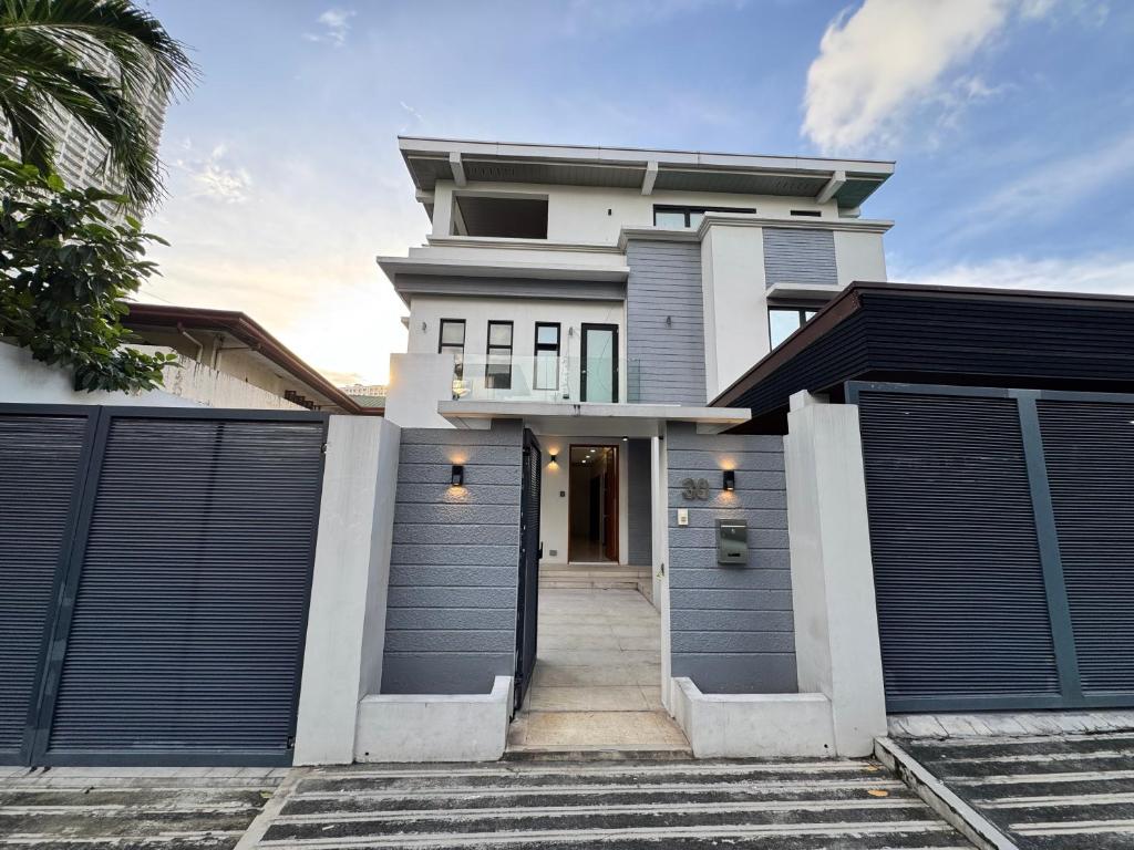 a house with two garage gates in front of it at Halika Villa & Capitolo events place near BGC in Manila