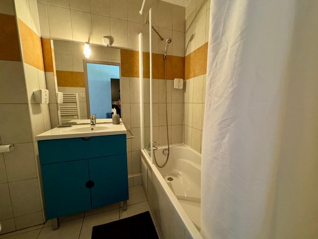 un bagno con un mobiletto blu, un lavandino e una doccia di Saint-Florent studio vue piscine a Saint-Florent