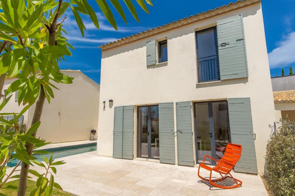 une villa avec piscine et une chaise orange dans l'établissement Maison Basilic, à Malaucène