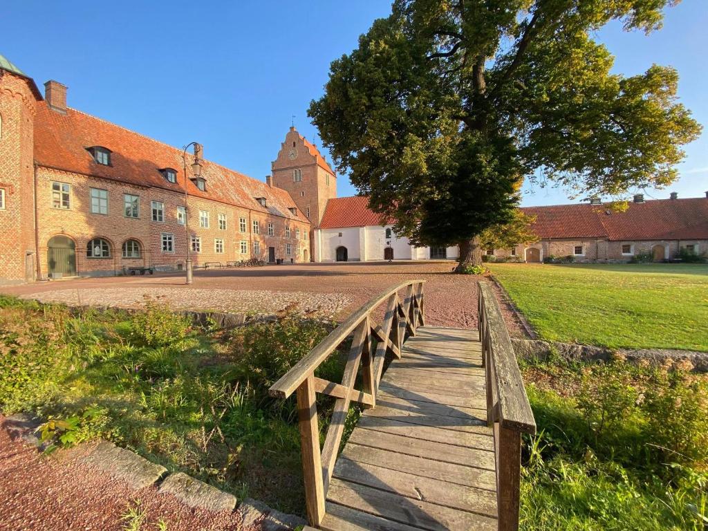 un ponte di legno davanti a un edificio con un albero di Bäckaskog Slott a Fjälkinge