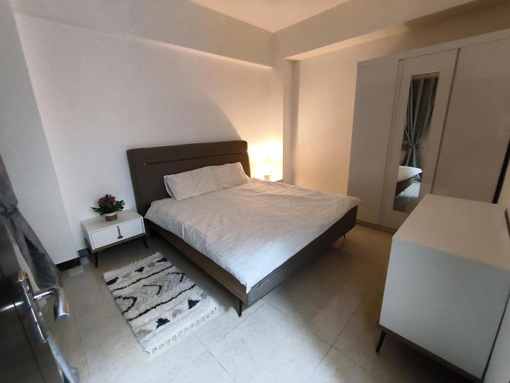 a small bedroom with a bed with a white bedspread and a rug at Elegant Ap in Muscat