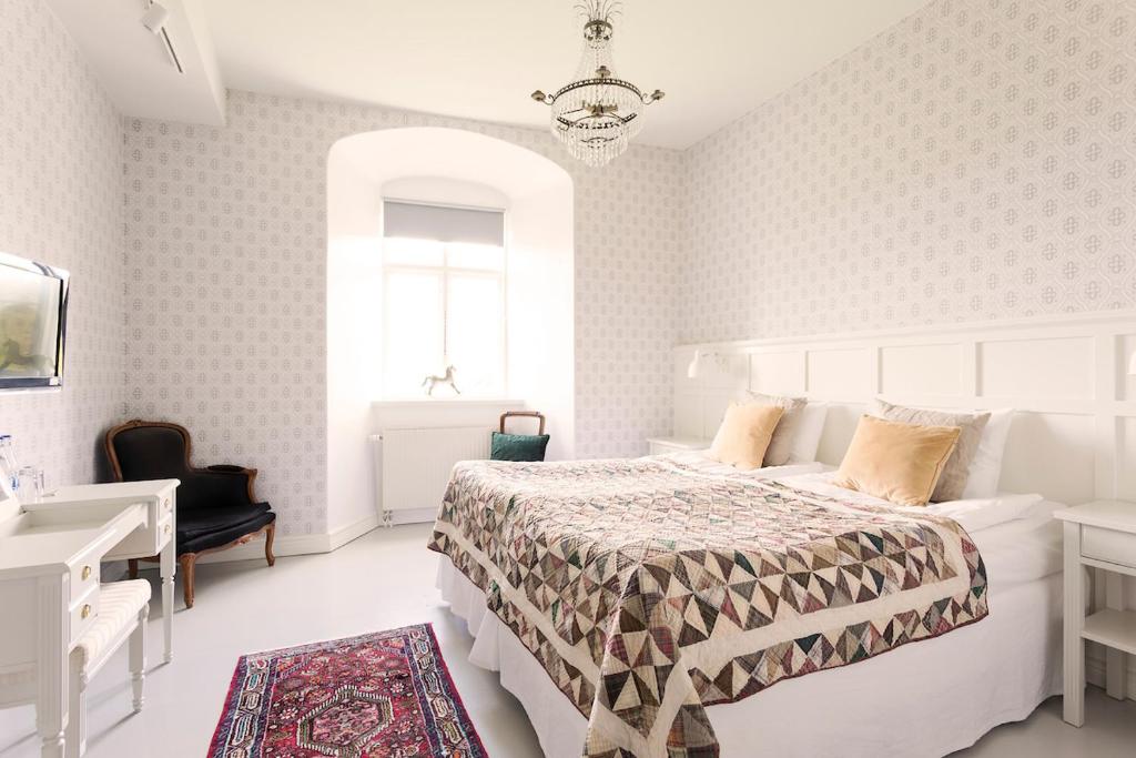 una camera da letto bianca con un letto e una scrivania di Bäckaskog Slott a Fjälkinge