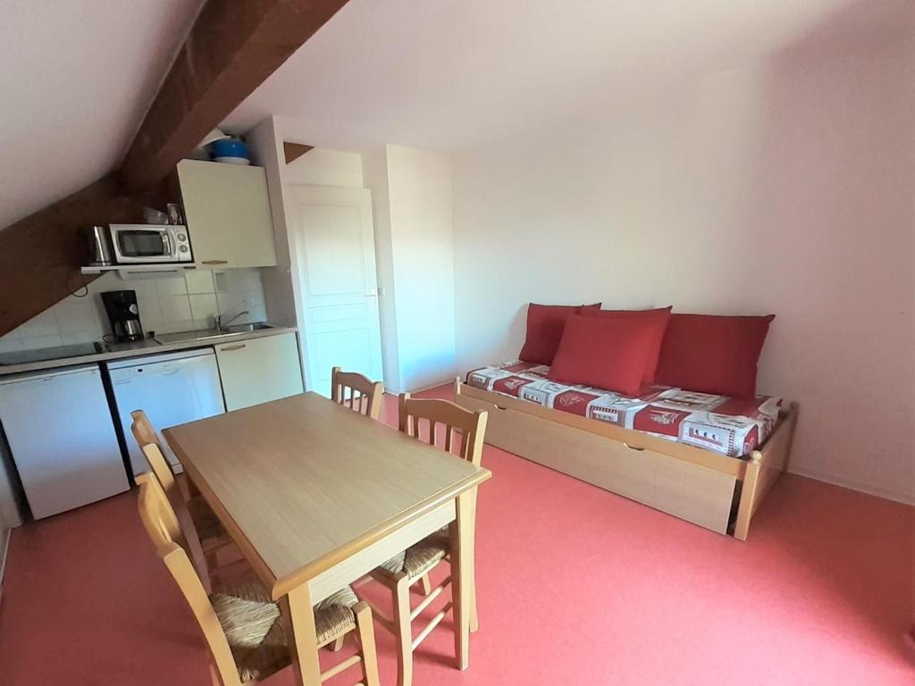 une petite pièce avec une table et un lit avec des oreillers rouges dans l'établissement Appartement Cozy 2 Pièces pour 4 Pers. avec Balcon - Résidence Les Chalets d'Aurouze, La Joue du Loup - FR-1-504-590, à Saint-Étienne-en-Dévoluy