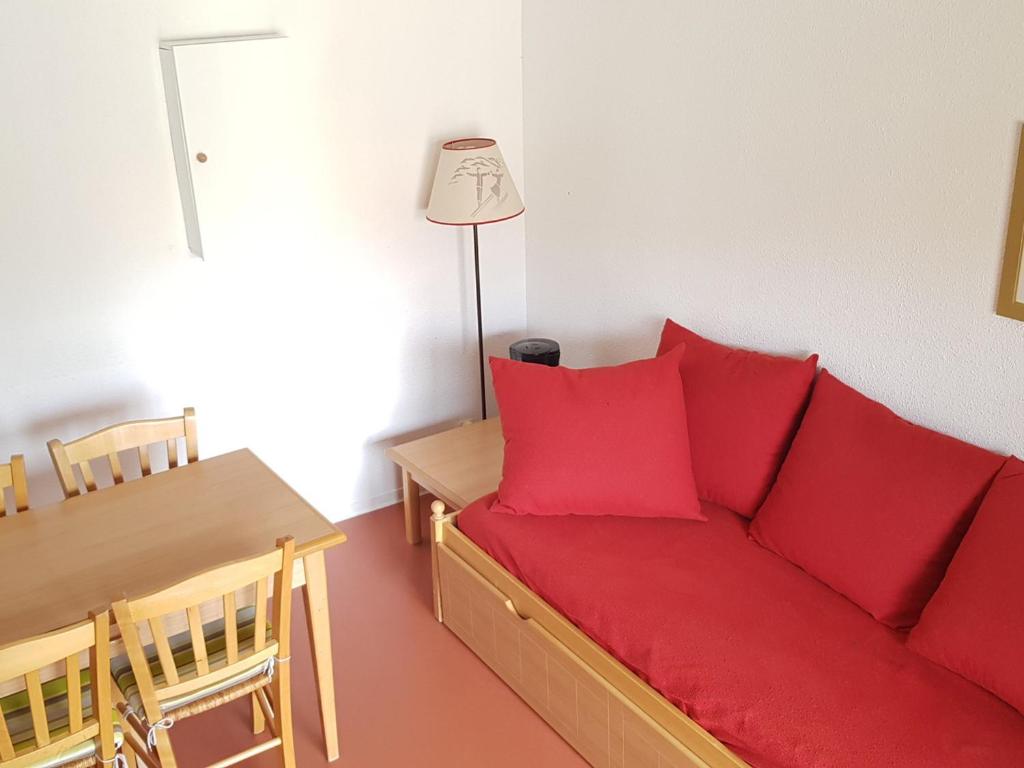 ein Wohnzimmer mit einem roten Sofa und einem Tisch in der Unterkunft Appartement Duplex 2P4 au Cœur des Chalets d'Aurouze à La Joue du Loup, Proche Commerces et Activités - FR-1-504-622 in Le Dévoluy