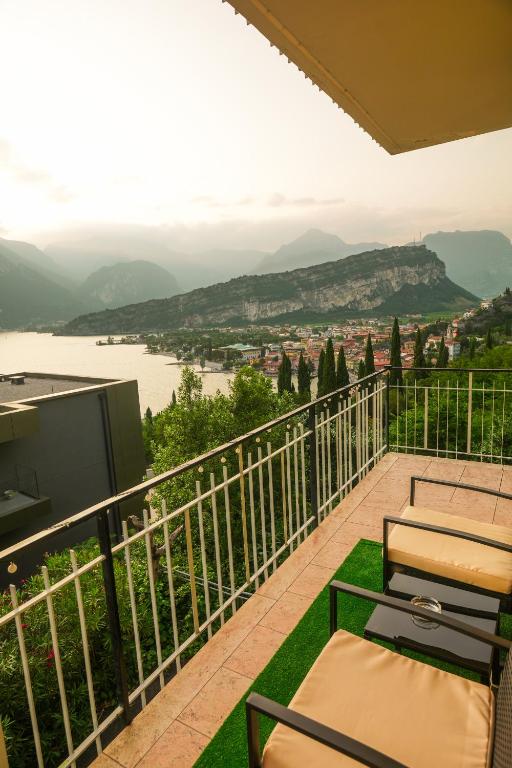 a balcony with chairs and a television and a view at Panoramic Lake View Apartment in Nago-Torbole