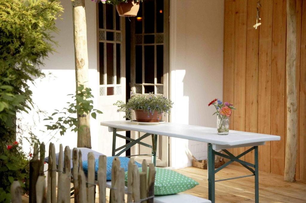 ein weißer Tisch auf einer Veranda mit einer Topfpflanze in der Unterkunft Casa di Jardin in Bergen
