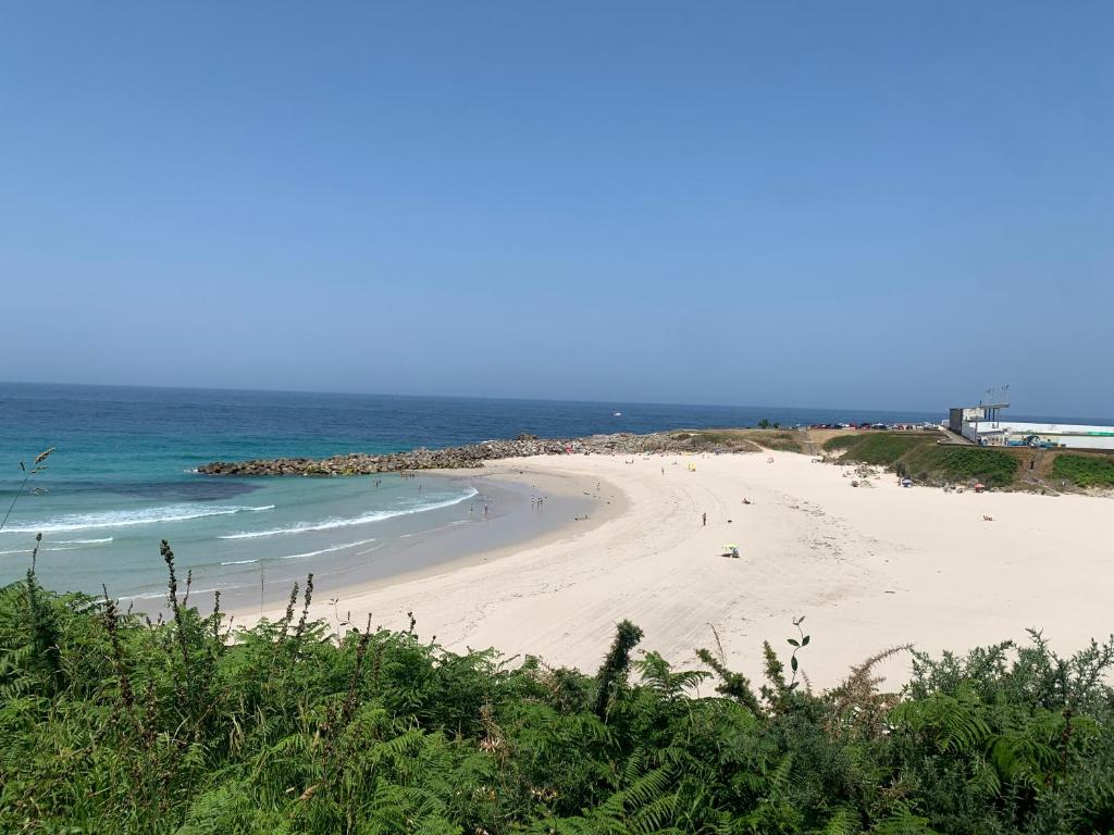 a beach with people walking on the sand and the ocean at A Marosa playa in Burela de Cabo
