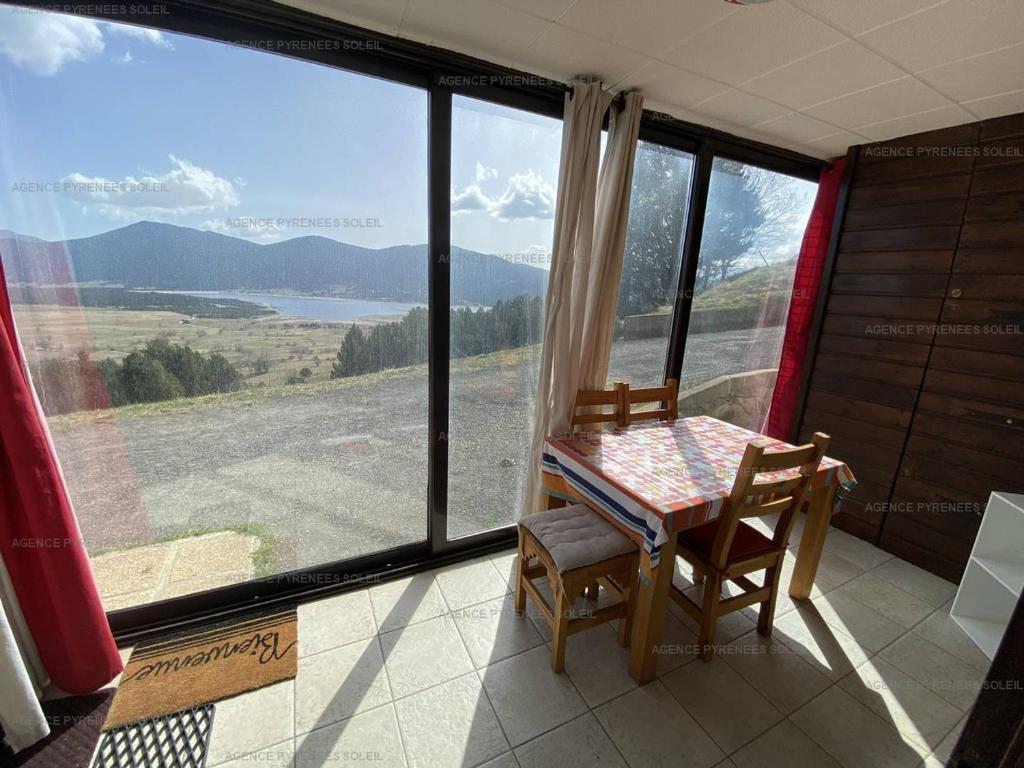 une table et des chaises dans une pièce avec une grande fenêtre dans l'établissement Bel F2/Cabine Les Angles, proches pistes, parking, classé 1 étoile - FR-1-295-141, aux Angles