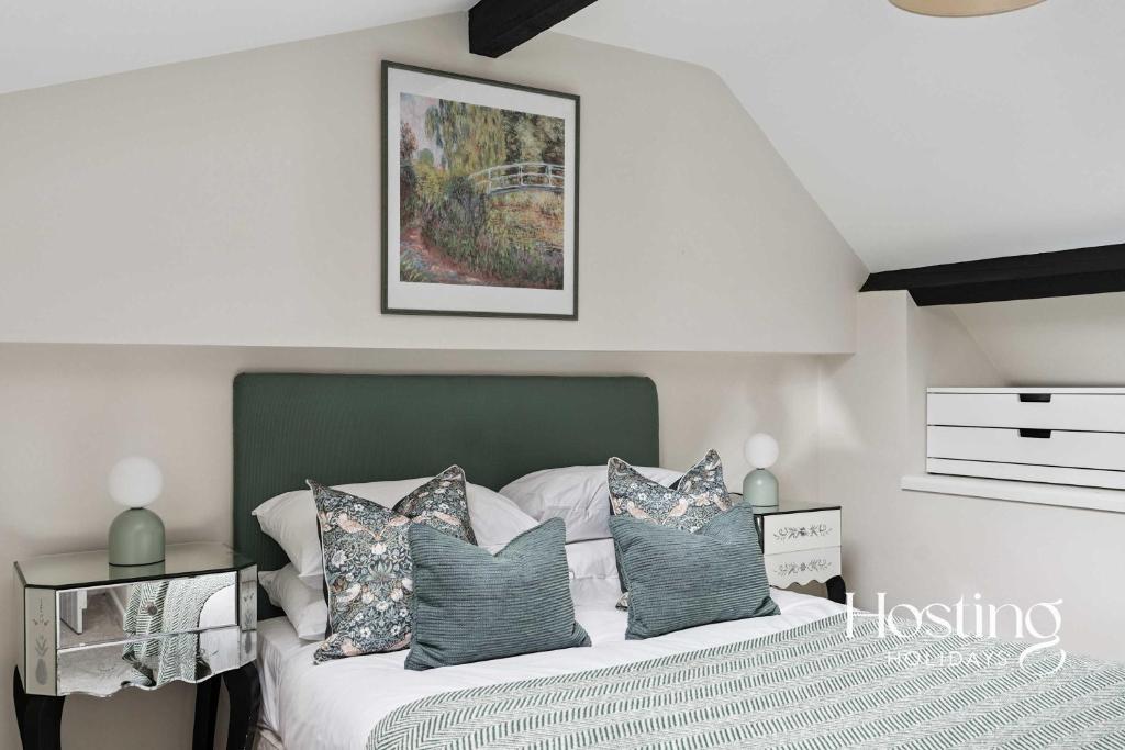a bedroom with a bed with a green headboard and pillows at Fairmile Loft - Cosy 1-Bed Stay in Central Henley in Henley on Thames