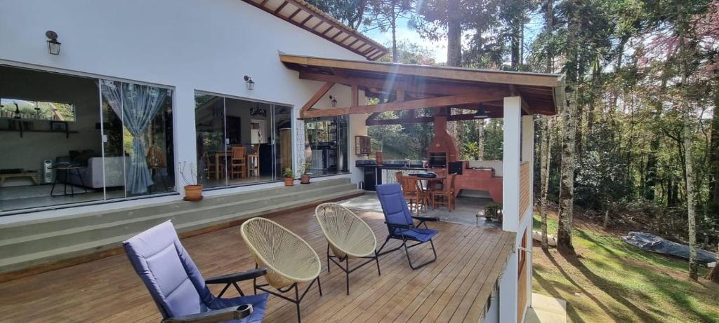 a house with a deck with chairs and a kitchen at Recanto na Mantiqueira - Casa 3Q a 2 km do centro in Gonçalves