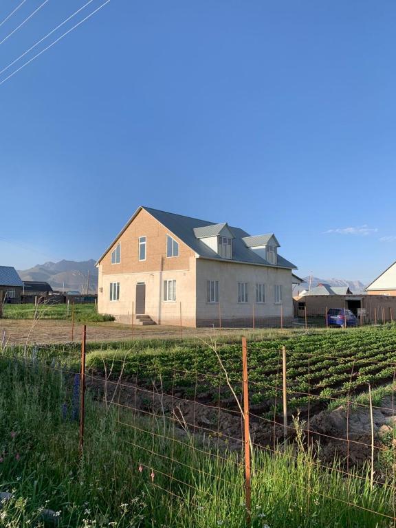 a house in a field next to a fence at Omurbek Guesthouse in Sary-Mogul