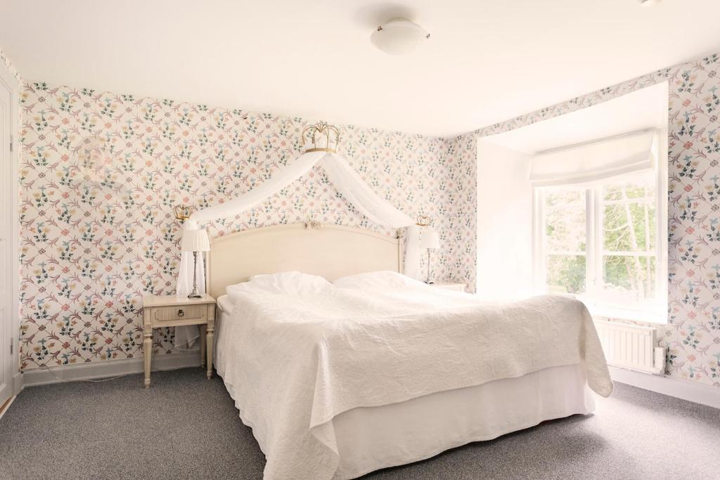 una camera da letto con un letto bianco e carta da parati floreale di Bäckaskog Slott a Fjälkinge