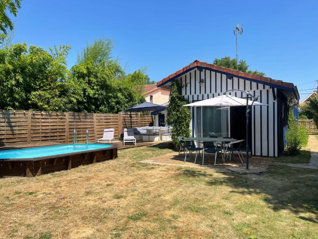 une arrière-cour avec une piscine, une table et un parasol dans l'établissement maison typique bassin d'Arcachon, au Teich