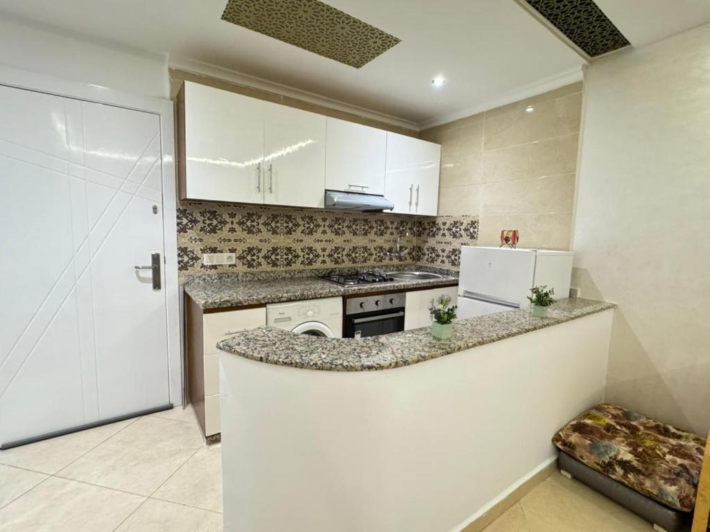 a kitchen with white cabinets and a counter top at Aura Douce Appartement in Martil