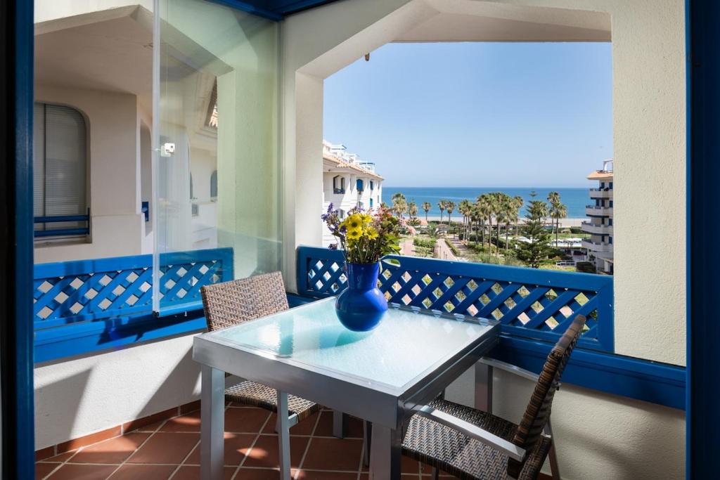 a table and chairs on a balcony with a vase of flowers at La Noria de Julie in San Luis de Sabinillas